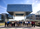 A large group of people stand in a line posing for a photo outside a modern glass-and-steel building.