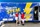 Three people pose in front of a brightly wrapped “Mobile STEM Lab” truck featuring a large yellow lightning bolt and the tagline “Energizing Education.” The two people on the sides wear matching red shirts that say “ExxonMobil Community Partners,” while the person in the middle wears a light blue polo and khaki shorts.
