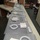 A long countertop is lined with identical white laptop power adapters and neatly coiled USB‑C cables, each set placed on individual sheets of bubble wrap.