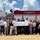 A group of people stands in front of a red fire truck labeled “MAGNOLIA ENGINE 6.” Several individuals in the center hold an oversized check from ExxonMobil made out to the Magnolia Fire Department for $10,000