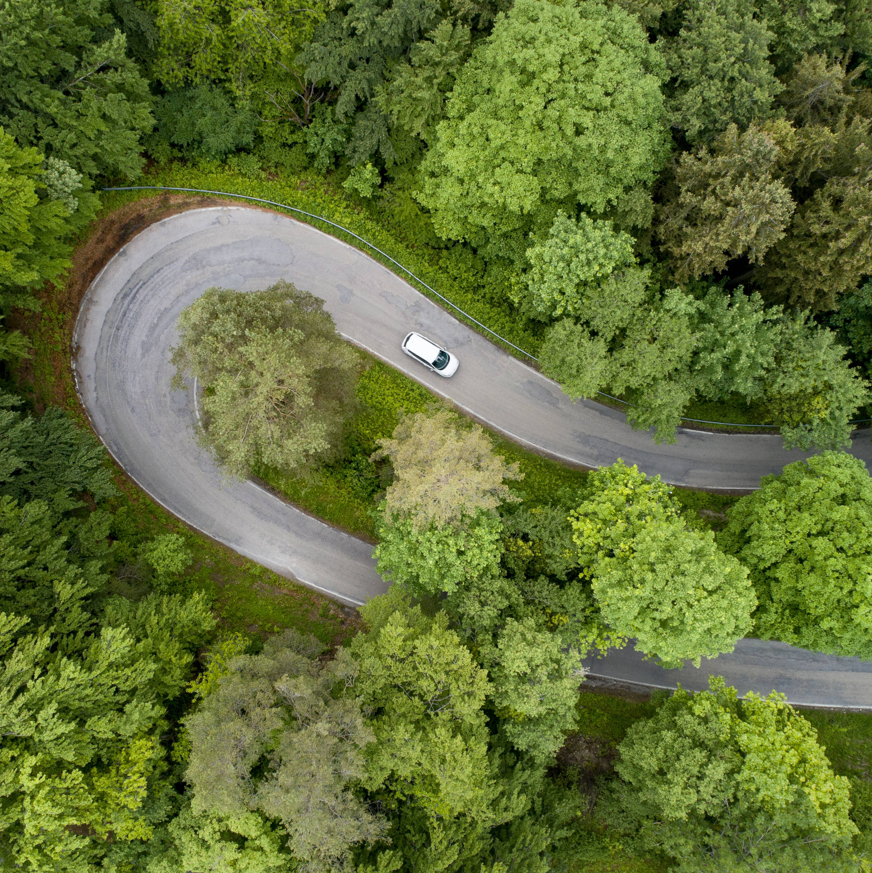 Aerial view of car driving on road with hairpin curve